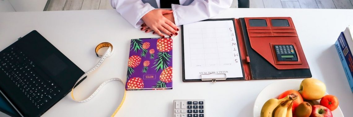 a woman sitting at a table with a plate of fruit and a calculator